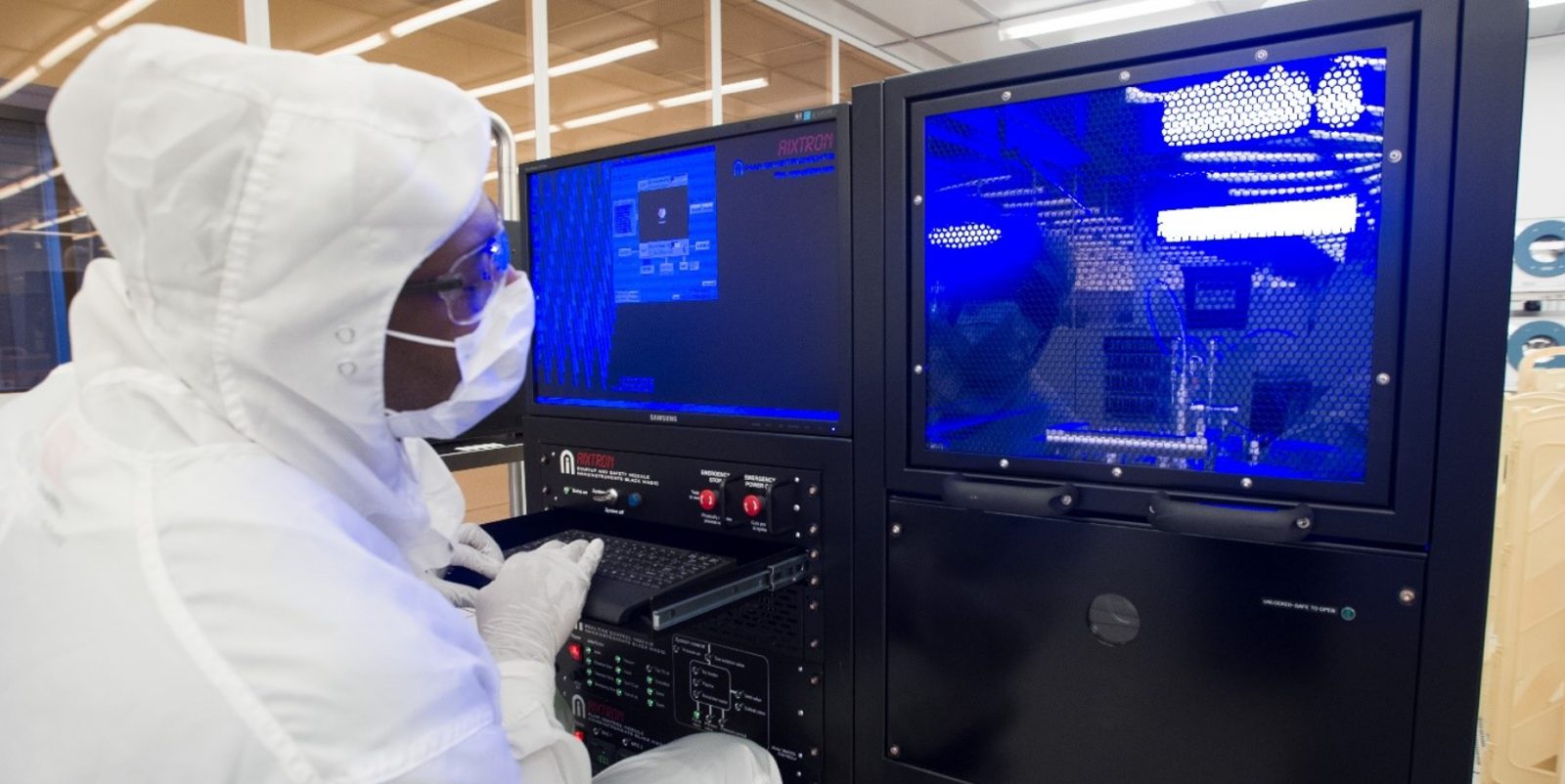 Researchers examining semiconductor fabrication equipment in a cleanroom
