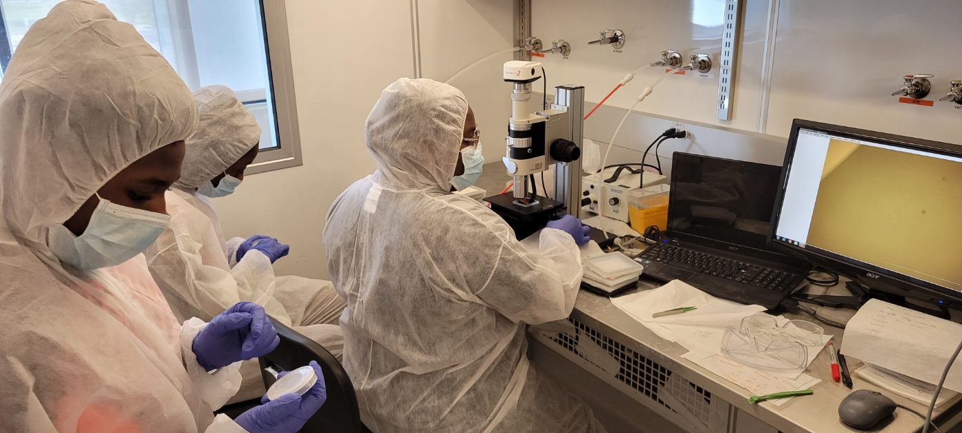 Students in cleanroom suits working with a microscope during an HBCU CHIPS Network training session
