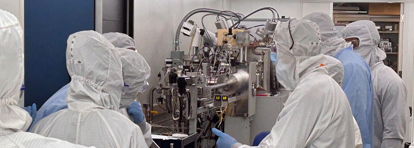 Researchers in cleanroom suits working around semiconductor fabrication equipment